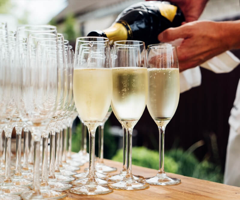 Metro Canteens Adelaide, Canteen Suppliers in Adelaide image of a waiter pouring champaign into lots of glasses at a function.